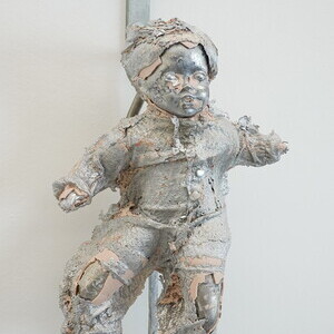 Anneliese Schrenk: Ich wäre gerne menschlich!, 2026, 52x43x16 cm, Unikataluminiumguss/Porzellanpuppe, RohrbahnhakenCourtesy die Künstlerinaus:Michael Kienzer & Anneliese Schrenk: 'Was tun Skulpturen ohne Aufsicht?', KULTUMUSEUM im Spiegelgitterhau