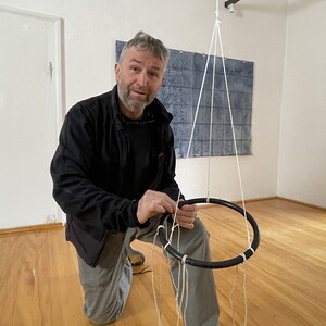 Wilhelm Scheruebl bei der Installation von: Wege, 2023  Schuhbänder: Tauschobjekte von Besuchenden, Holzring 144 Minusaquarelle, je 15x20 cm Rauminstallation  Sonnenblumenschatten hell, I, 2022/23 Tusche auf Transparentpapier,  29x42 cm 