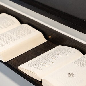 Jochen Höller, * 1977 in Amstetten (AT), lebt in Wien (AT), Wissen : Glauben, 2016, Collage, Papier auf Karton, gerahmt: 114,6 x 182,5 cm; Auf der Ablage: (Holz): 182,5 x 18 cm: Die Bibel, die Lehren des Buddha, der Koran, die Upanishaden, die Tor