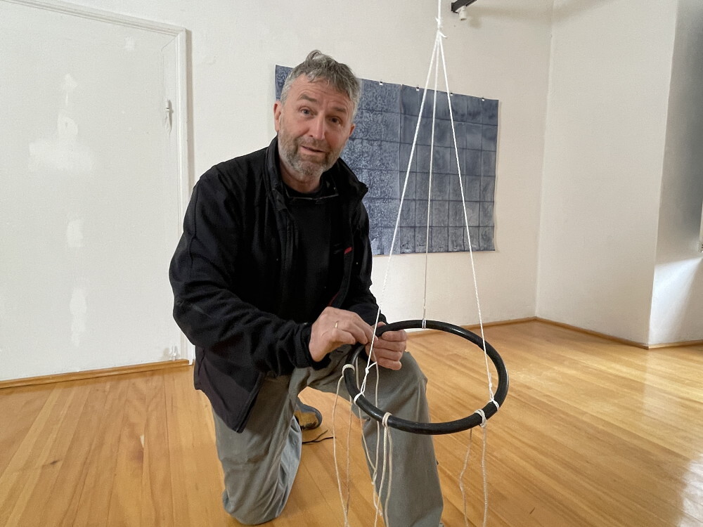 Wilhelm Scheruebl bei der Installation von: Wege, 2023  Schuhbänder: Tauschobjekte von Besuchenden, Holzring 144 Minusaquarelle, je 15x20 cm Rauminstallation  Sonnenblumenschatten hell, I, 2022/23 Tusche auf Transparentpapier,  29x42 cm 